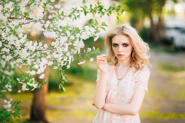 Fototapeta na wymiar Beautiful young girl standing among the flowering trees. White flowers.