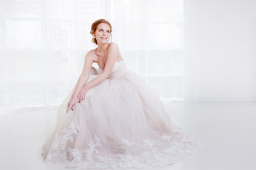 Portrait of a beautiful girl in a wedding dress. Sitting on the couch and laughs happily