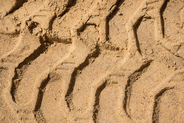 Trace of the tractor on the sand. The background of the industrial sand for construction works. Natural material for bricks and concrete products - on-site production work.