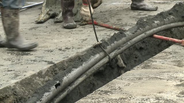 An excavator is extracting several underground pipes with the help of construction workers. Water leak on a street in Taipei, Taiwan.