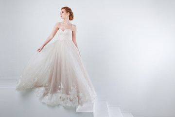 Fototapeta na wymiar Portrait of a beautiful girl in a wedding dress. Bride in luxurious dress on a white background