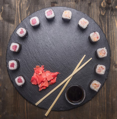 Japanese food, sushi with salmon and tuna, fresh ginger,  soy sauce and chopsticks lined up on a tray of chalk boards, frame, space for text, top view
