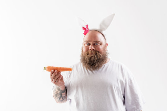 Man holding a carrot wearing bunny ears