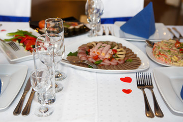 Served with Cutlery and food on table. A Banquet with food and snacks with a luxurious setting on a white tablecloth.