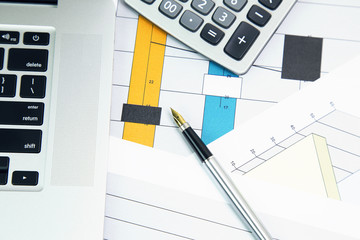 Business accessories and graphics, charts. Business concept, working, analyzing, sticky note on laptop with calculator on graph background 