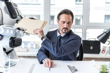 Gloomy mature man is sitting at table