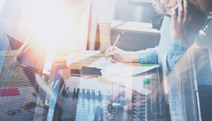 Fototapeta premium Business people working process concept.Young coworkers working together in modern office.Woman using mobile phone.Double exposure,skyscraper building blurred background.Horizontal.