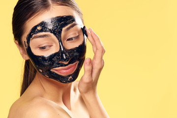 Woman in a cosmetic mask on a yellow background