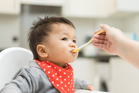 Asian Baby Boy Eating Blend Food On A High Chair