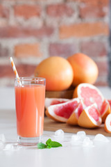Freshly pressed grapefruit juice with mint leaves and ice on the brick wall background closeup.