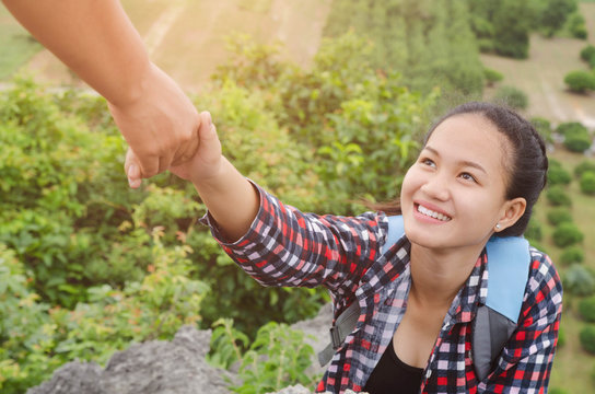 hand hold helping young woman traveler on top mountain