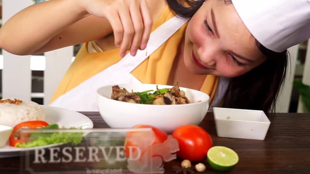 Video footage of a young female chef garnishing Indonesian food Sop Buntut while wearing hat and uniform in the restaurant