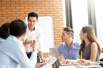 Young casual Asian businessman presenting his work in the meeting