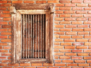 Fototapeta na wymiar antique wooden window with iron bars on brick wall