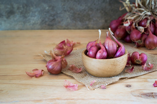 the shallots in bowl on old wooden table with old wallpaper background