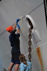 Malerarbeiten an einem Boot, Rostfelcken werden mit weißem Lack angestrichen 