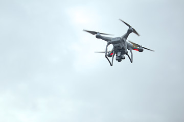 Fototapeta na wymiar White drone with digital camera flying on sky background.