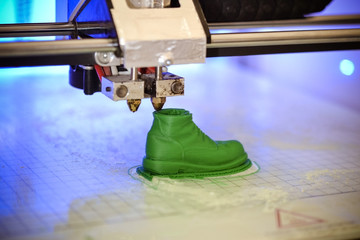 3D printer prints the form of molten plastic green close-up. Automatic three dimensional 3d printer performs plastic modeling in laboratory. Progressive modern additive technology