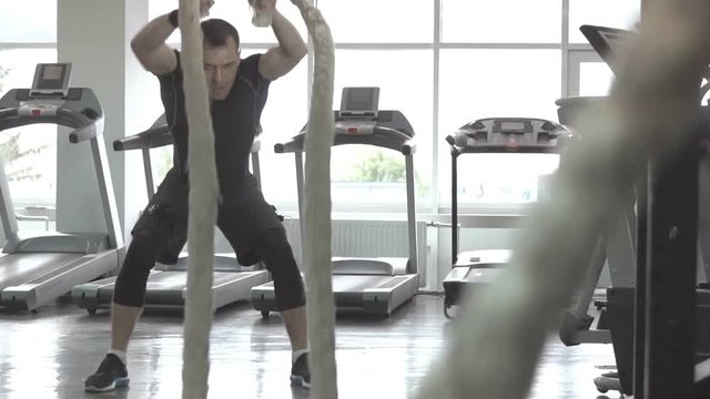 Man with battle rope in functional training fitness gym