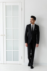 Confident businessman in black suit standing full-length