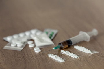 lines and plastic packet of cocaine or other drugs. white powder narcotic and syringe on the wooden...