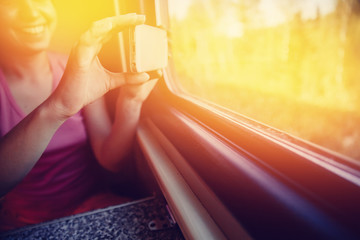 girl is taking pictures in a train window on a mobile phone. Concept social mobility, travel by rail, social networks.