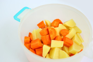 Chopped and sliced carrot and potatoes in plastic pot.