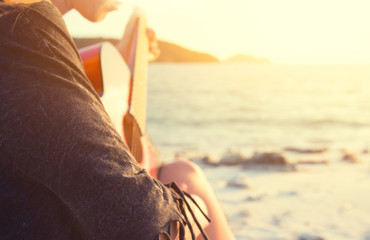 woman playing guitar on sunset beach