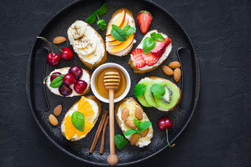 Assorted summer sweet snacks. Bruschetta or sandwiches with fruit and berries. Top view with copy space