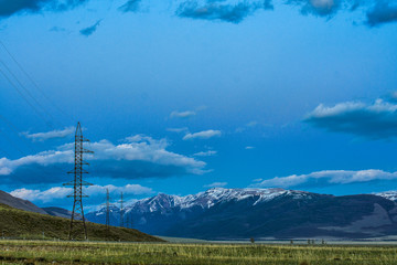Obraz premium High voltage transmission towers with mountains on background 