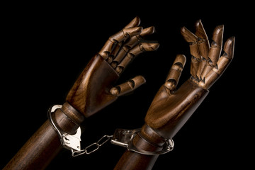 Handcuffs attach two black hands together. With copy space text. Isolated on black background. Studio Shot.
