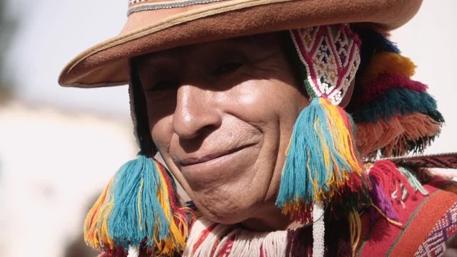 Native quechua man using a colorful hancrafted chullo and a highlander hat smiling and singing. Slow motion