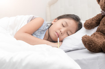 sick girl lying in bed with a thermometer