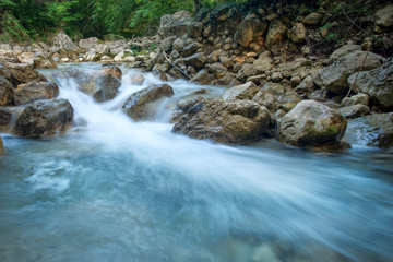 Obraz premium Forest creek with waterfalls. Water cascades over rocks. blue and crystal clear water in mountain river.