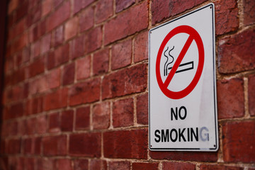 No smoking sign on a red brick wall.