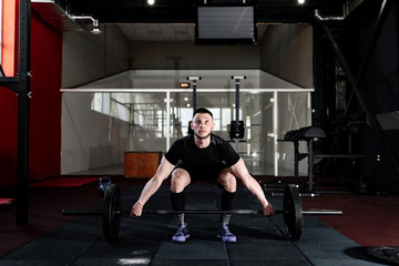 Fit young  athlete lifting the barbell in gym. Gym training. Full body length portrait