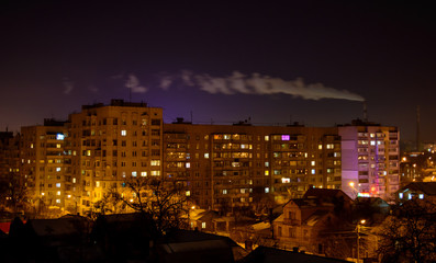 Fototapeta na wymiar Photo of buildings at night with factory smoke above them