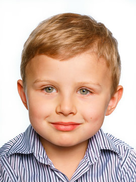 His first experience to make photo for passport or ID card. Emotionally grimacing little boy with blond hair and bright green eyes. White background.