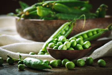 Delicious ripe green peas lying on a wooden table.