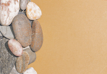 Fototapeta na wymiar Gray and white pebbles on brown textured paper, background