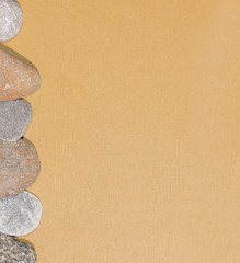 Fototapeta na wymiar Gray and white pebbles on brown textured paper, background