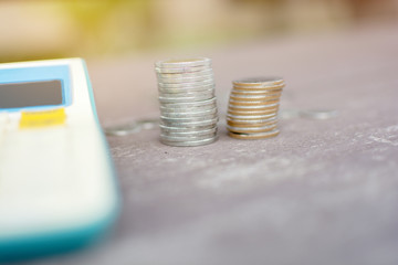 Two piles of silver coin and calculator on the wooden table