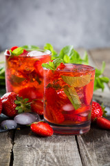 Strawberry mojito and ingredients on rustic background