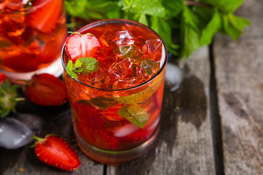 Strawberry mojito and ingredients on rustic background