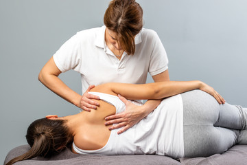 Female therapist manipulating shoulder blade on young female patient.