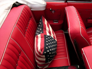 Kissen mit amerikanischer Flagge auf dem roten Rücksitz eines amerikanischen Cabriolet der...