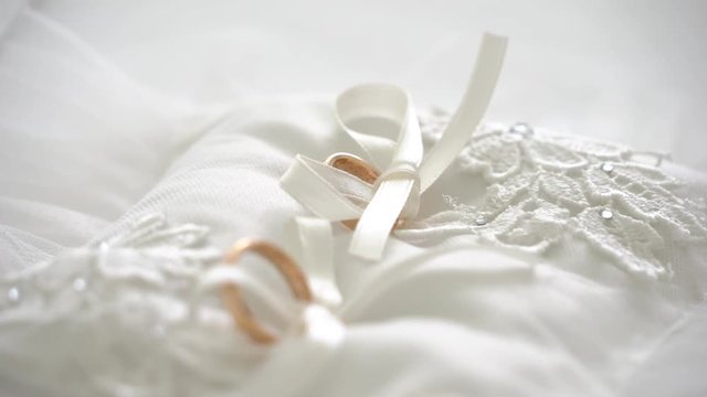 Wedding rings on a white pillow with ribbons 