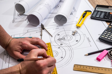Mechanical engineer with work at technical drawings and work tools