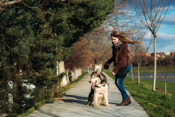 A girl is walking with a dog along the embankment. Beautiful Husky dog. The river. Spring.