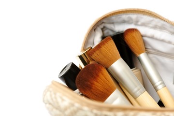 Open cosmetic bag with makeup brushes and a set of cosmetics. Isolated on white